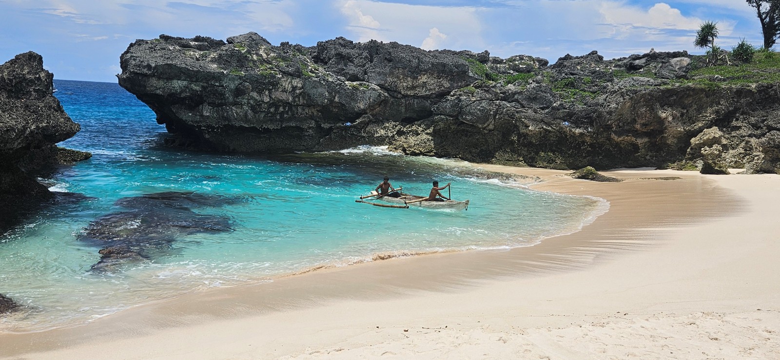 Pirogues traditionnelles posées sur le sable entourées de rochers à Mandorak Beach, Sumba